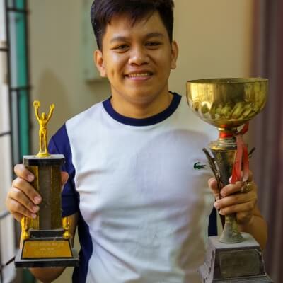 Coach Geo holding two trophies during his competitive years